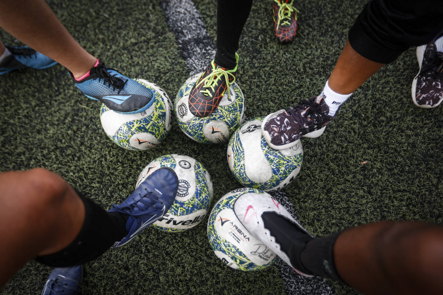 Players pose for a picture with their feet on balls during a training session led by women's football coach Dilma Mendes, 59, at the Arena 2 de Julho Football School located in the city of Camacari, Bahia state, Brazil, on July 5, 2023. Brazilian Dilma Mendes, does not remember how many times she was arrested as a kid. Her crime? Playing football in a country that banned women from the beautiful game for nearly four decades. (Photo by RAFAEL MARTINS / AFP) (Photo by RAFAEL MARTINS/AFP via Getty Images)